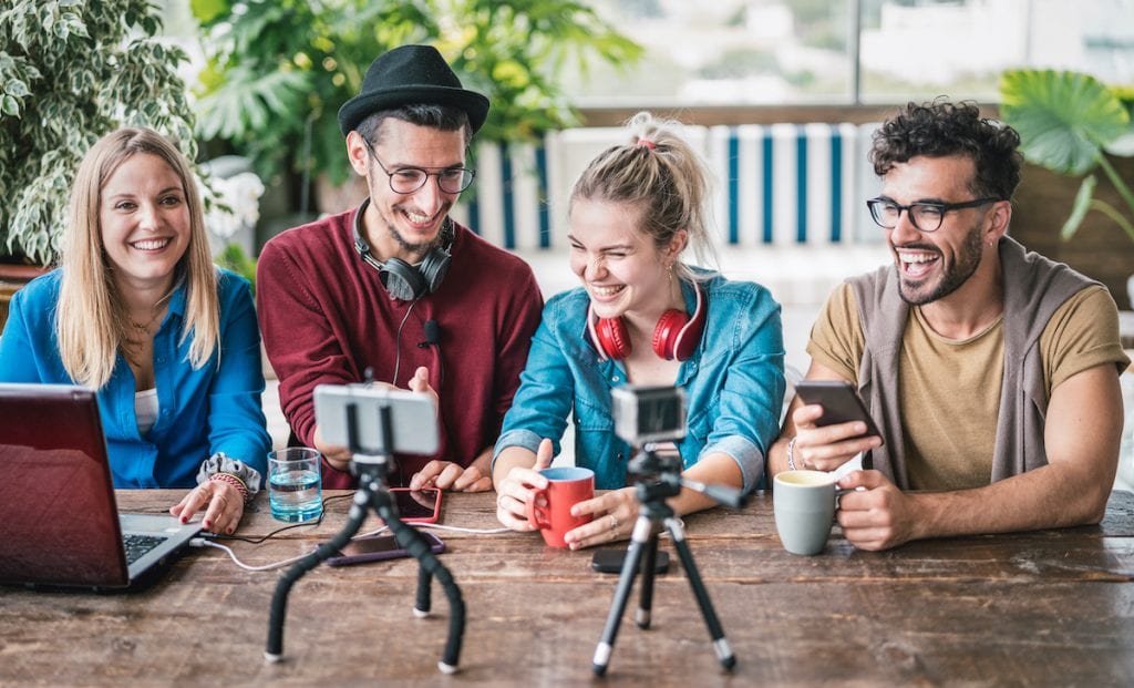 Young friends group sharing info on streaming platform with webcam - Startup marketing concept with millennial guys and girls having fun vlogging live talk feed on social media network - Bright filter